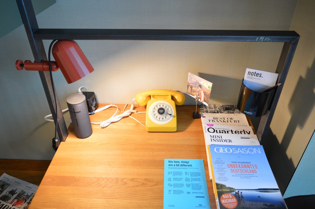 white and red desk phone on brown wooden table